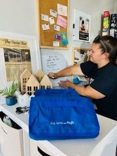 A woman sitting at a desk with a blue bag.